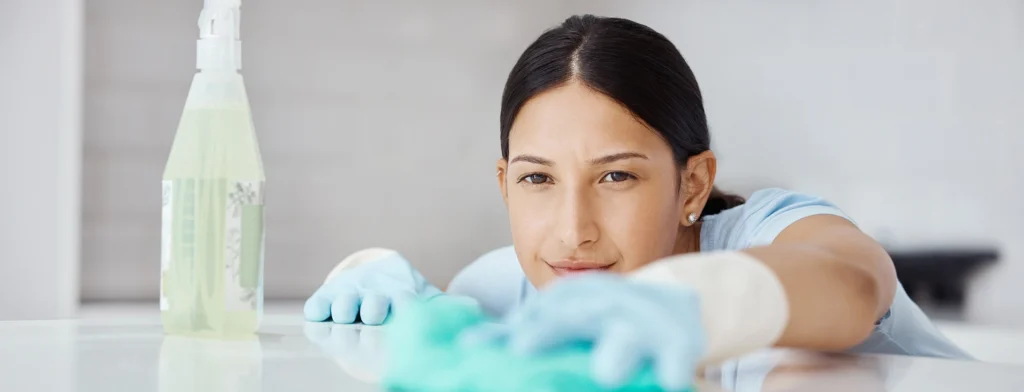 Limpeza profissional a limpar uma superfície lisa com um pano de microfibra e spray de limpeza.